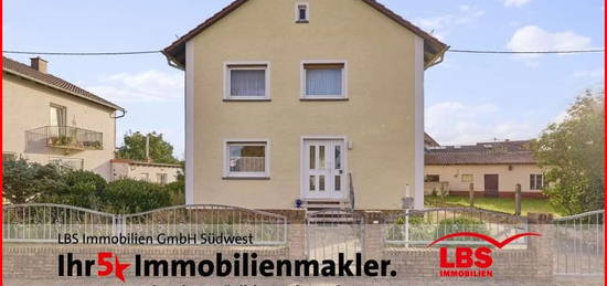 Freistehendes Einfamilienhaus mit sonnigem Garten, Nebengebäude und Garage.