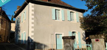 Maison en pierre avec garage ouvert attenant.